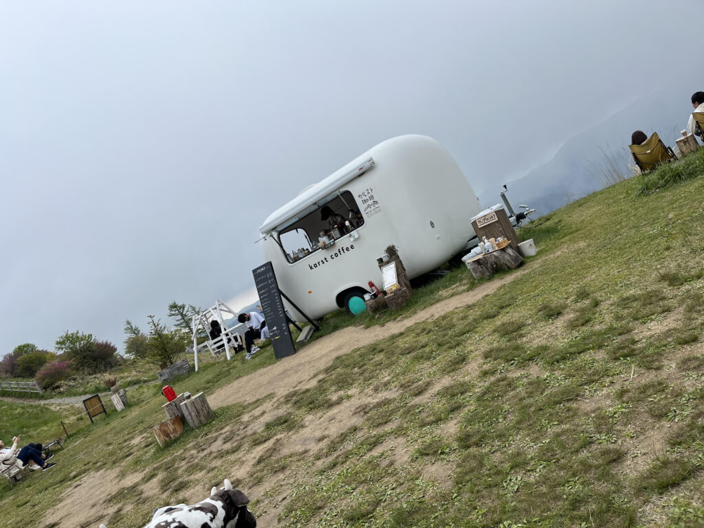 カルスト珈琲の白い販売車と周りの風景。雲に覆われている。